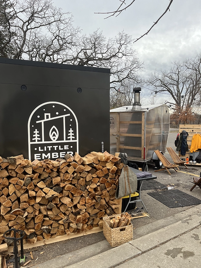 Two saunas with a stack of firewood.