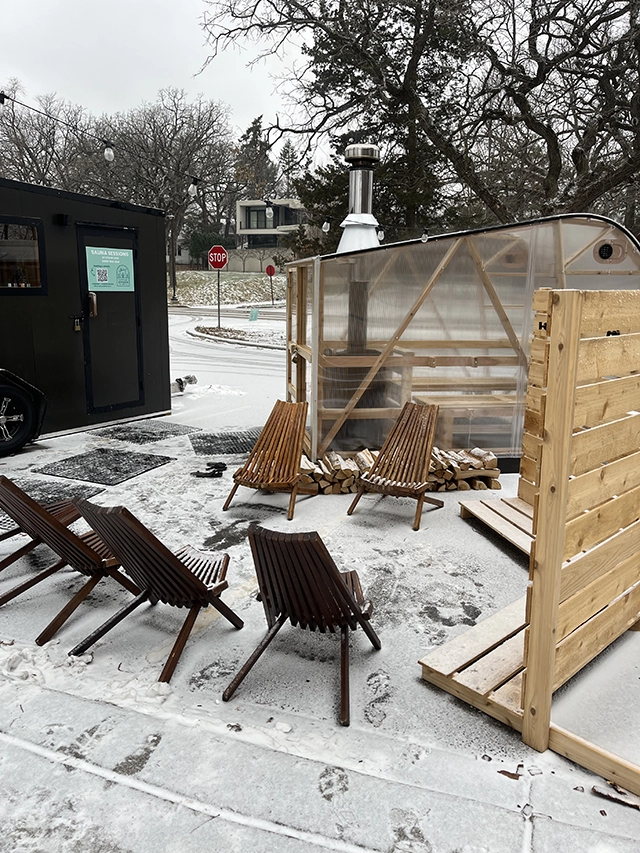 Snow covered lounge chairs near two saunas.